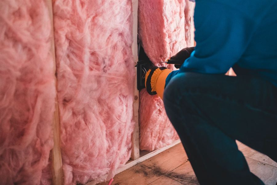 Glasswool insulation batts being installed between wall studs