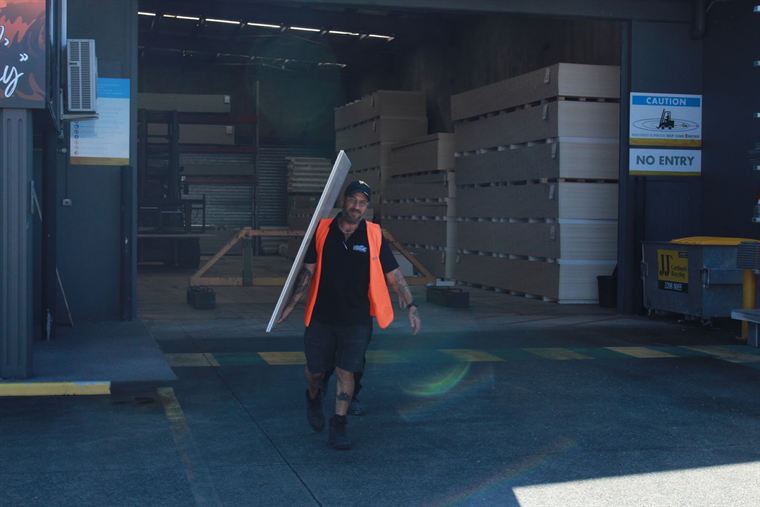 Bayside Plasterboard staff member carrying a plasterboard sheet