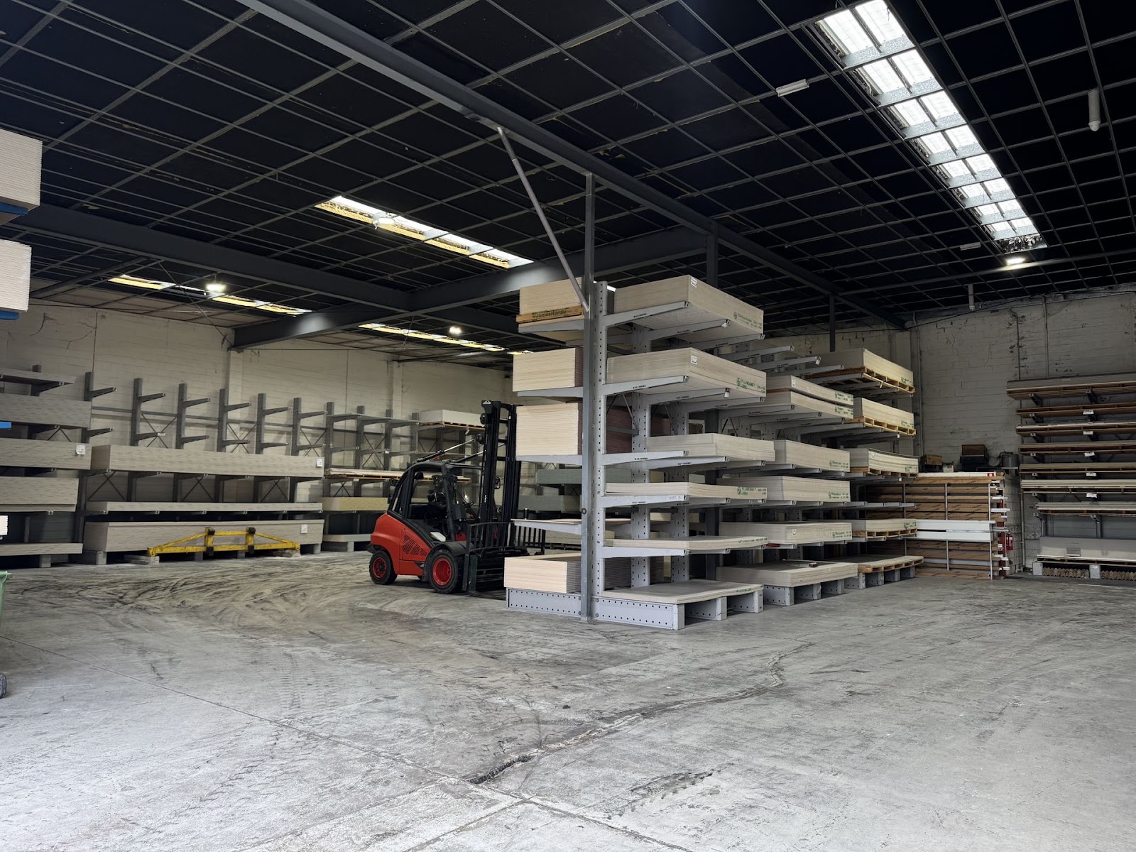Linde forklift beside a tall cantilever rack of plasterboard, with more racks of board along the back wall of the wareho